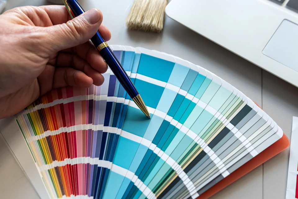 Intérieur moderne avec un serrurier en salopette bleue et chemise à carreaux installant une poignée de porte, accompagné d'une cliente assise observant les travaux