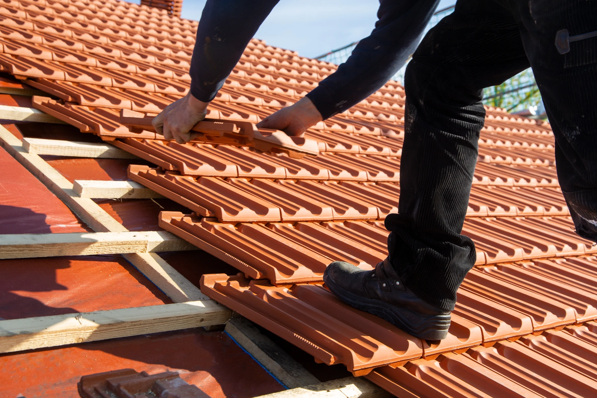 Couvreur travaillant sur toiture résidentielle par temps ensoleillé