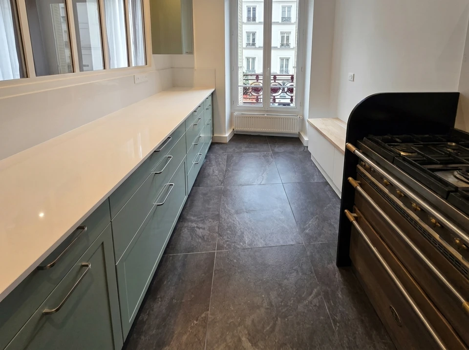 Intérieur en cours de rénovation avec pose de revêtement de sol stratifié gris clair partiellement installé sur chape béton brute